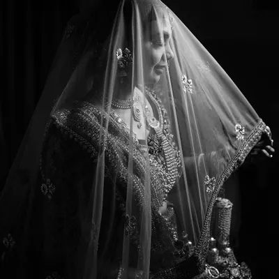 A bride veiled in mystery and elegance. This black and white portrait uses the sheer dupatta and soft light to create a dreamy, timeless, and artistic image.