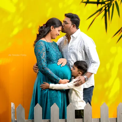 A perfect family portrait showing the excitement of a growing family. The older brother-to-be gives a sweet kiss to the baby bump in this colorful and happy studio session.