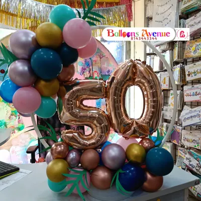 A compact and elegant tabletop balloon decoration for a 50th milestone celebration. This arrangement features a small ring with balloons and a large rose gold number '50', perfect for an office desk or a small party at home.