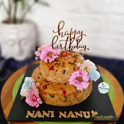 A simple and sweet mini tea cake tier. This two-tiered tutti frutti cake is adorned with a few flowers, perfect for a small, charming celebration for grandparents.