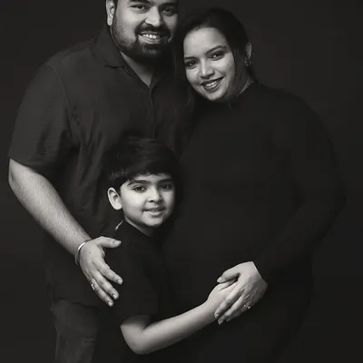 A classic black and white maternity portrait of a family of three, soon to be four. The dark background puts all the focus on their expressions of love and anticipation.