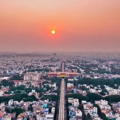 A stunning sunset over the Bengaluru cityscape, with the sun perfectly aligned over a central thoroughfare, capturing the vast expanse of the urban area.