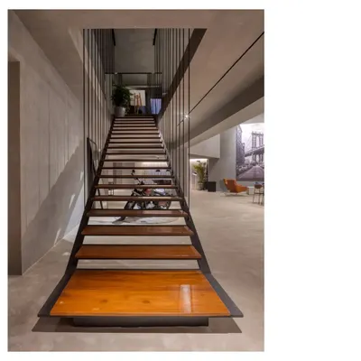A seamless gray concrete gallery and party space. We designed this area to be highly adaptable, with a long communal table and a dramatic staircase, allowing atmosphere and people to make the space.