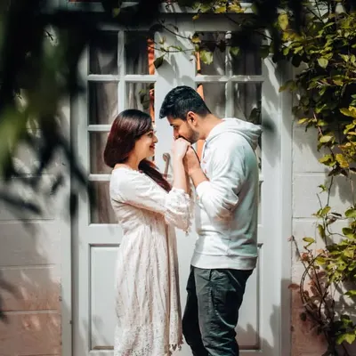 A tender moment shared between a couple, framed by natural greenery. This pre-wedding photo captures the gentle intimacy and quiet promises that are part of every love story.