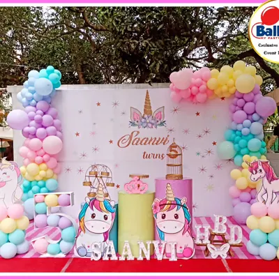 A dreamy unicorn-themed fifth birthday party. This outdoor setup features pastel balloon columns, unicorn cutouts, and a 'SAANVI' marquee.