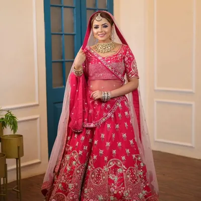 A full-length view of a classic bridal look, featuring a vibrant pink lehenga paired with a gold Kundan choker set. This is a timeless choice for any bride on her wedding day.