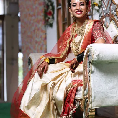 My bride Varsha, looking absolutely radiant for her wedding day. This is a classic South Indian bridal look with a beautiful white and red Kanjeevaram saree, temple jewellery, and a bright, confident smile.