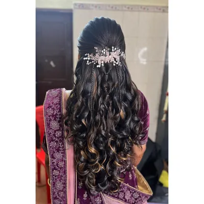 This is a popular reception hairstyle. It features a half-updo with cascading curls, accented with two delicate braids and a sparkling hair vine for a touch of glamour.