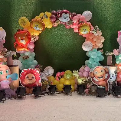 This fun animal-themed decoration was for a naming ceremony. I used a grass backdrop, a balloon arch, and lots of cute animal and baby character cutouts to create a playful scene.
