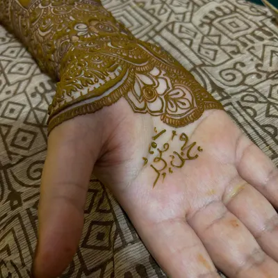 A close-up of the palm, where the groom's name is beautifully written in Arabic script, nestled within the intricate patterns.