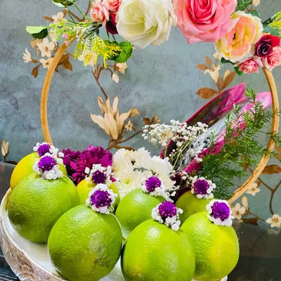 An elegant fruit platter featuring fresh limes and a beautiful floral arrangement. I use ornate silver and gold-rimmed baskets that you can rent for displaying fruits and other offerings.
