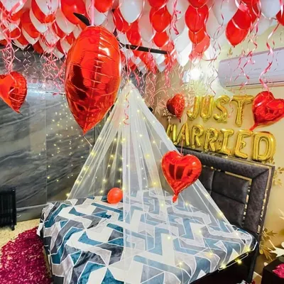 A close-up view of our romantic room decoration service. The bed is adorned with a light canopy and fairy lights, while the ceiling is covered with red and white balloons, creating an immersive and celebratory feel.