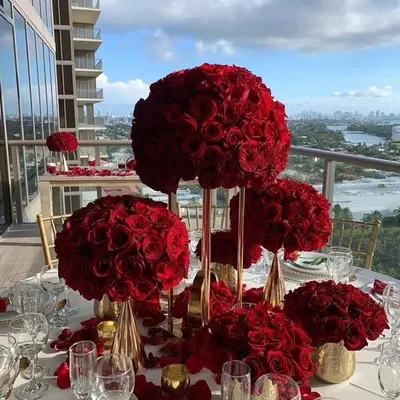The epitome of romance and luxury. These tall centerpieces, featuring large, perfect spheres of red roses, create a dramatic and passionate atmosphere for an exclusive dinner setting.