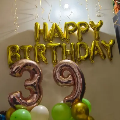 A simple and stylish home birthday decoration. This setup with foil number balloons and a 'Happy Birthday' banner is part of our affordable home decor segment, perfect for intimate celebrations.