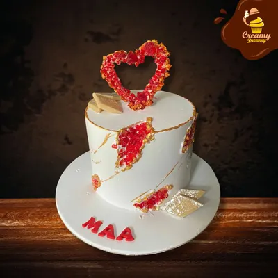 A modern and artistic cake for "Maa." This design features a white fault line style with red crystal details and a beautiful heart-shaped topper, showing love in a contemporary way.