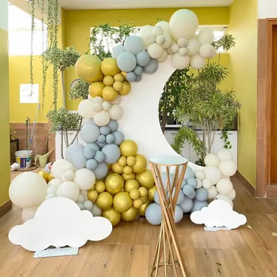 A beautiful and modern backdrop with a crescent moon shape. The balloon garland in shades of gold, grey, and white creates a sophisticated and dreamy look, perfect for a baby shower or elegant birthday.