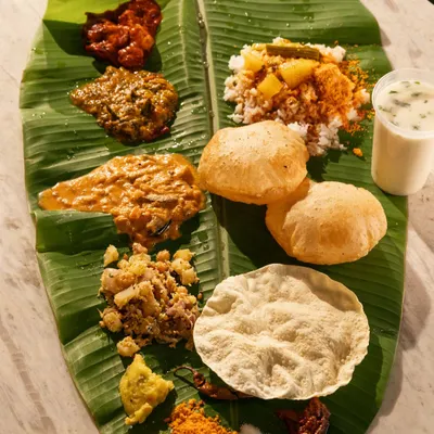 A traditional South Indian meal served on a banana leaf. This overhead shot captures the variety of colors, textures, and dishes in a single frame.