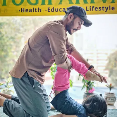 Our instructor provides gentle assistance to a young student in a backbending pose, ensuring safety and encouragement.