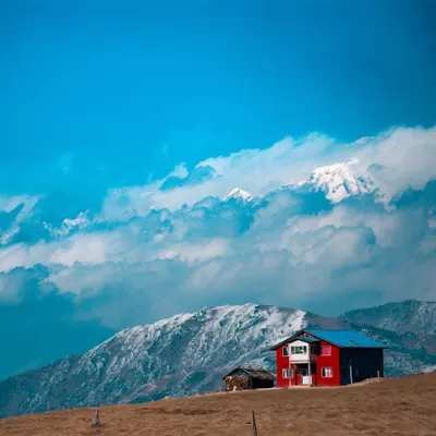 A lone house stands against the backdrop of the mighty Kanchenjunga range. This is a typical, stunning view you'll encounter on the Sandakphu trek, where we stay in cozy tea houses along the India Nepal border.