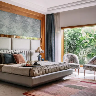 This master bedroom is a perfect example of serene luxury. The large window offers an uninterrupted view of the private garden, making you feel connected to nature. The upholstered headboard and soft, layered textiles create an inviting and restful environment.