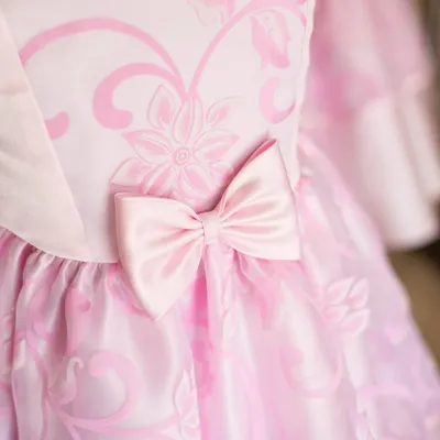 A close-up of a beautiful pink dress, showing the subtle floral pattern on the fabric and a perfectly crafted satin bow. It’s these small details that create a truly elegant finish.