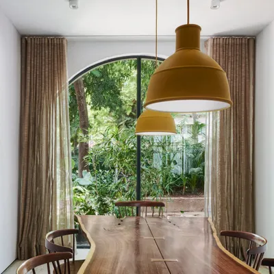 Arched French windows in our studio dining area offer a captivating glimpse into the lush greenery outside. This seamless integration of indoor-outdoor living is a core principle of our design approach.