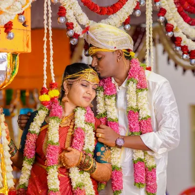 A tender moment during a South Indian wedding, where the groom kisses the bride's forehead. This shot captures the love and blessings of the ceremony.