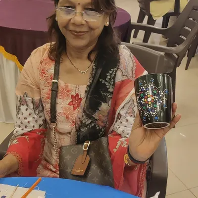 A member of the Sakhi Ladies Group proudly displays the intricate dot mandala design she painted on her mug during our art party.