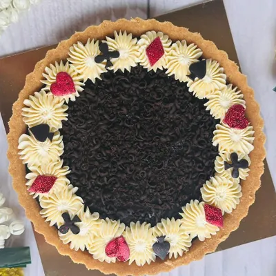 For Diwali card parties, I designed this special chocolate tart. It features a rich chocolate filling and is decorated with buttercream and edible card suit symbols for a festive touch.