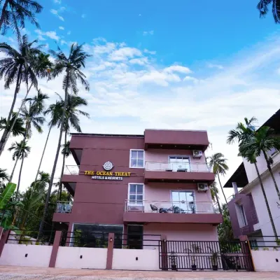 The front exterior of The Ocean Treat Hotel in Alibaug, framed by coconut trees. This shot establishes the property's tropical setting and welcoming facade, crucial for hotel marketing.