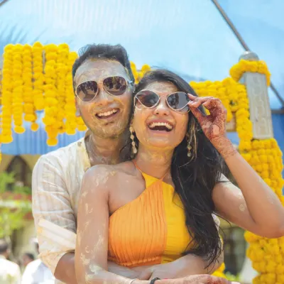 Pure fun and laughter captured during a Haldi ceremony, as the couple, covered in turmeric paste, poses with sunglasses.