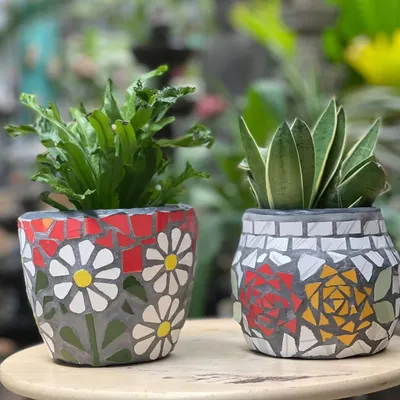 A pair of mosaic planters, each with a unique floral pattern made from hand-cut ceramic tiles. These one-of-a-kind terracotta pots will add a splash of color to your garden all year round.