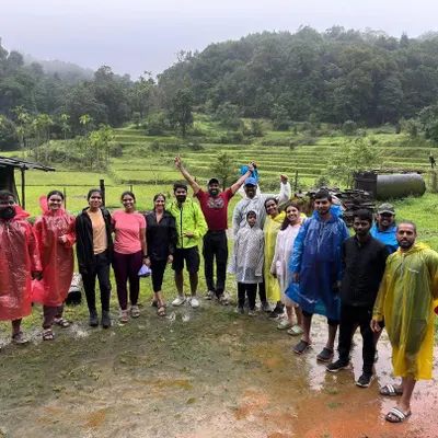 A happy group photo in the rain, standing in front of lush green paddy fields. The monsoon brings out the best smiles.