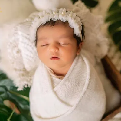 This classic swaddle keeps the baby snug and content. I styled this shot with a soft lace headband and fresh green leaves for a pure and natural feel.