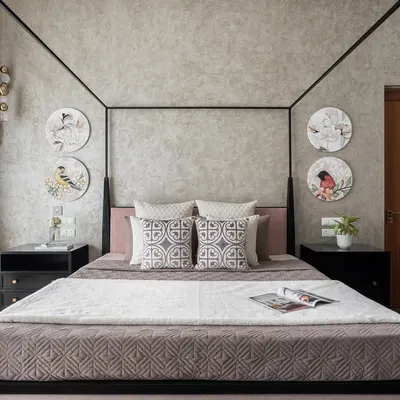 This master bedroom features a modern four-poster bed as its centerpiece. We used a textured wallpaper and circular art pieces depicting birds to add a touch of nature and personality to this earthy, tranquil space.
