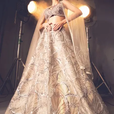 This stunning gold lehenga is a masterpiece of design and detail. The intricate, fan-like embroidery creates a sense of movement and grandeur, perfect for a bride or for making a statement at a grand celebration.