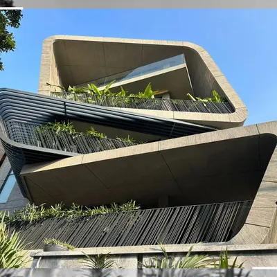 The dynamic, multi-level balconies of this curvilinear building. The facade is designed as a series of flowing concrete ribbons, creating unique perspectives from each level and seamlessly blending indoor and outdoor living spaces.