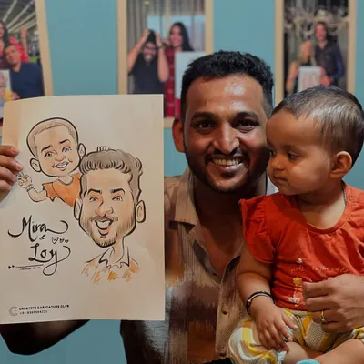 A heartwarming moment with a father and his baby girl, holding a caricature of the two of them. These are the family memories I am honored to help create.