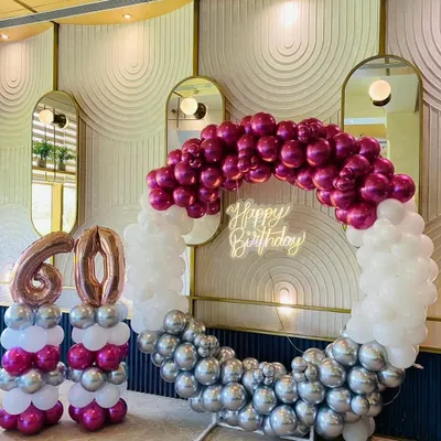 A stunning 60th birthday celebration. We used a half-and-half balloon ring with chrome magenta, white, and silver balloons, a neon sign, and large foil number balloons to create an elegant and modern photo-op area.