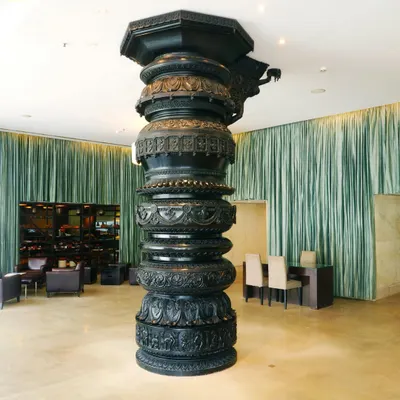 Our lobby is defined by this magnificent black wooden pillar, hand-carved by artisans from Cauvery Emporium. It's a striking ode to Indian artistry, blending Hoysala craftsmanship with a modern aesthetic.
