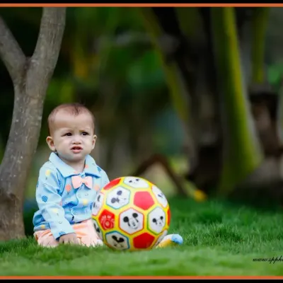 An outdoor setting is a perfect playground for a kid's photoshoot. This image captures a quiet, candid moment of a young boy with his ball in a park.