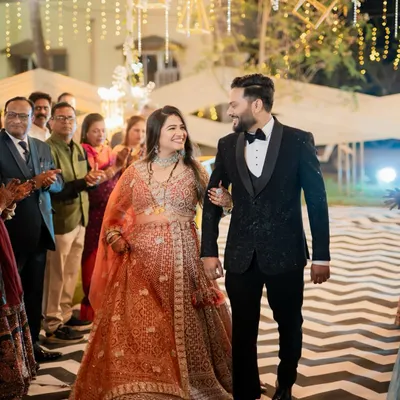 The grand entrance of the bride and groom at their reception, walking down an aisle lined with cheering family and friends.