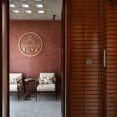 The first look into our studio, framed by a brick-clad doorway. This view offers a glimpse of the red oxide wall and our brass logo, setting the tone for our design aesthetic right from the entrance.
