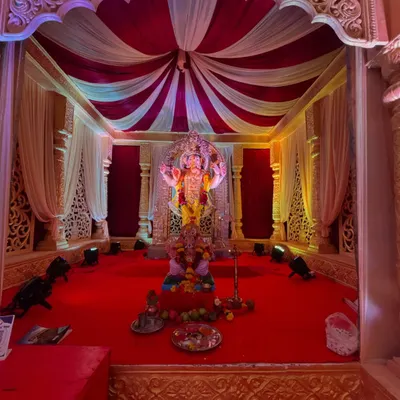 A grand and traditional mandap setup for Ganesh Chaturthi. I used a classic red and white color scheme with elegant draping, detailed pillars, and focused spotlights to make the Ganpati idol the center of attention.
