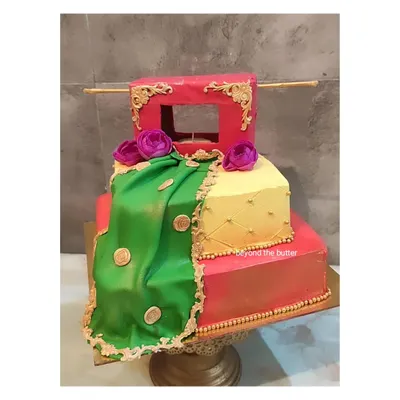 This three-tier Haldi theme cake is designed to look like a traditional dholki and draped fabric. The vibrant green, yellow, and red colors, along with gold detailing, make it a perfect centerpiece for the ceremony.