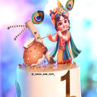 A vibrant first birthday cake with a Little Krishna theme, complete with a flute and peacock feathers. We teach how to use edible prints and fondant to create detailed characters.