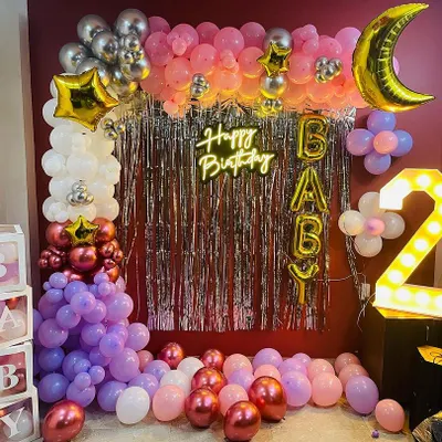 This is a "Happy Birthday Baby" setup I created for a second birthday. It features a silver foil curtain, a balloon wall in pink and purple tones, a light-up number '2', and a "Happy Birthday" neon sign.