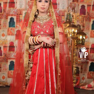 A beautiful full-length portrait of a model styled as a traditional bride. She is wearing a complete kundan set with a classic red and white chooda, showcasing a timeless wedding day look.