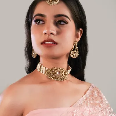 A polished makeup look for a jewellery brand shoot. The soft glam on the eyes and a neutral lip color ensure the model's beauty enhances the antique-finish choker and maang tikka without competing with them.