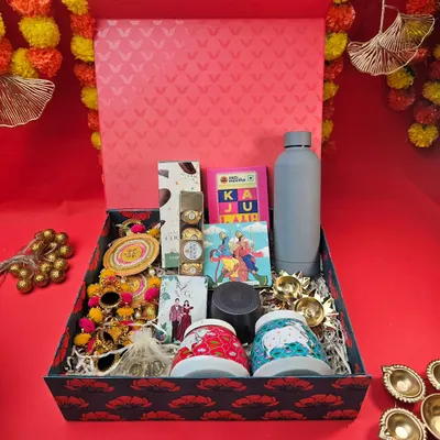 Our Diwali hampers are designed to impress. This large, patterned box is filled with a variety of goodies, including unique mugs, a water bottle, traditional torans, diyas, and sweet treats.